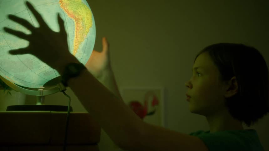 A girl takes a lamp shape like a globe off a platform