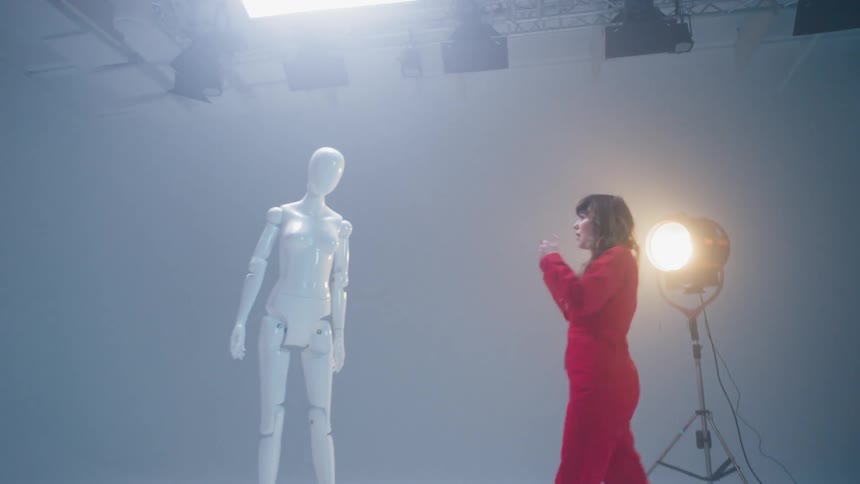 A woman dances near a mannequin in a studio