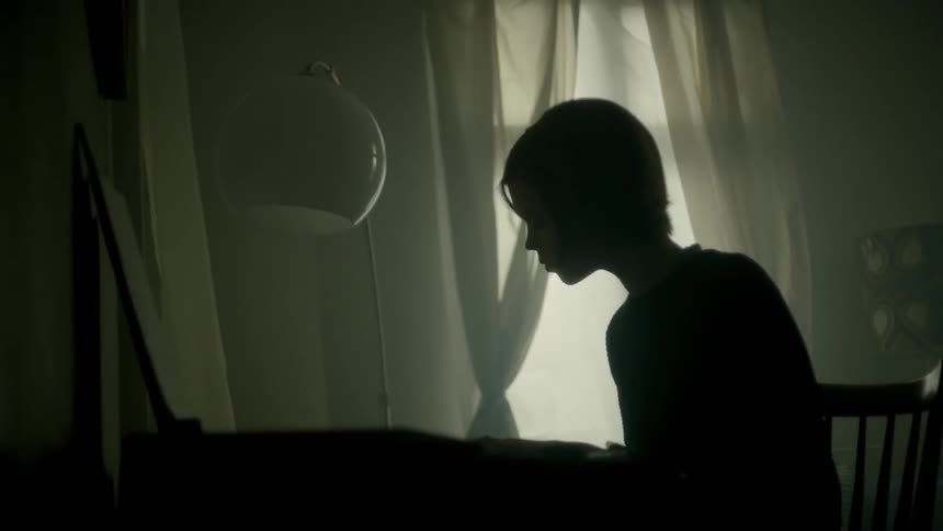 A person plays a piano in a dark room