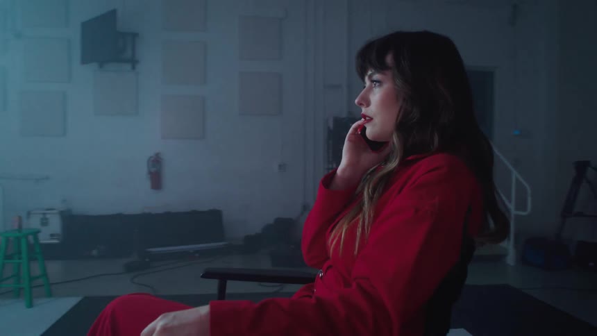A woman sits in a director style chair with a smart phone