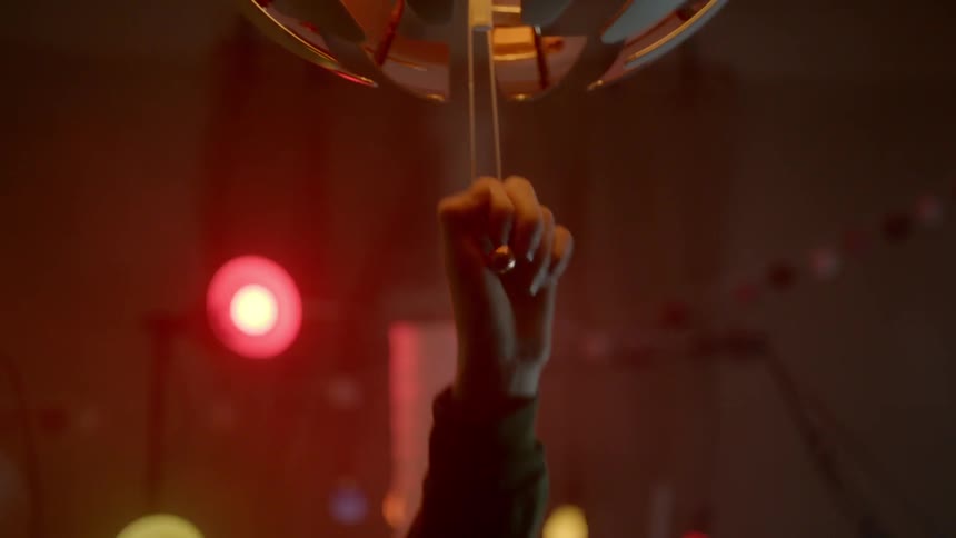 A hand opens and closes a lamp shade hanging from the ceiling