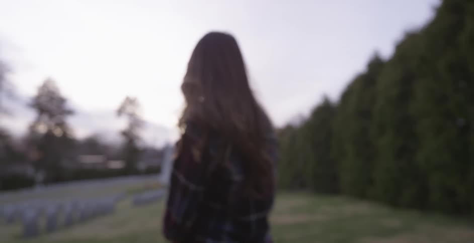 A woman stands in a cemetery