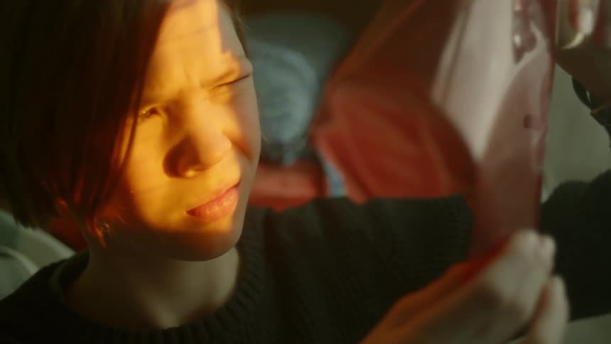A young boy holds a sheet of plastic up to the sunlight