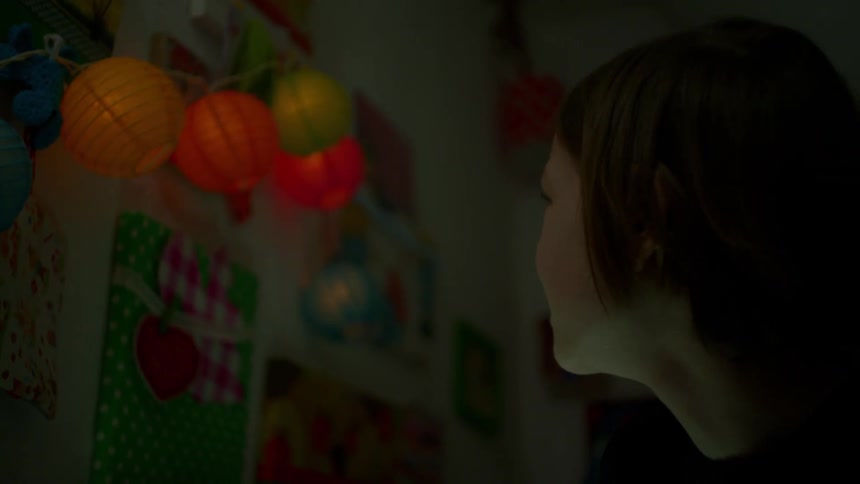 A young girl looks at lit up lights in a room