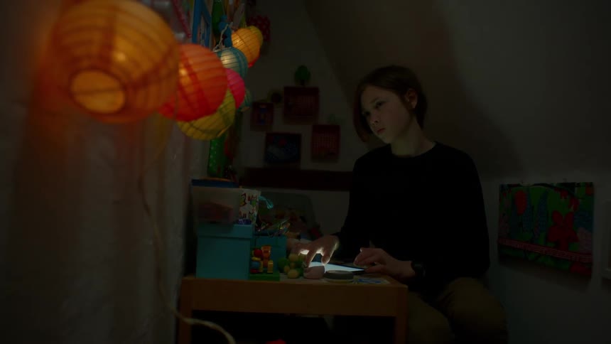 A woman is using her tablet in the dark corner
