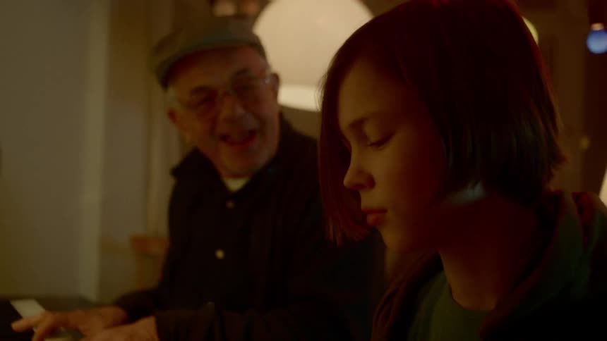 A young boy and his grandfather play the keyboard together