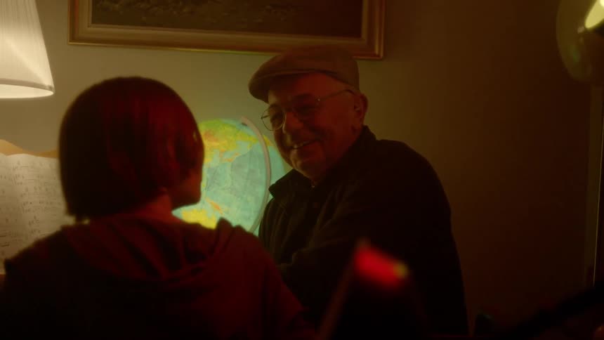 An old man sits next to a child at a piano