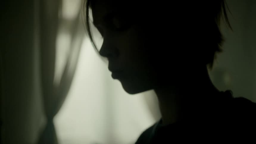 Boys silhouette plays the piano in the dark room