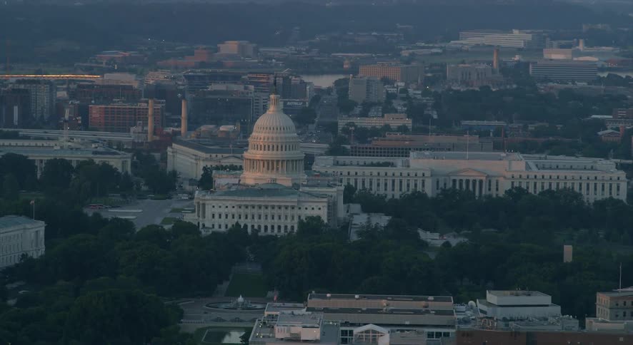 The u.s. capitol building stands amidst other buildings on a hazy day