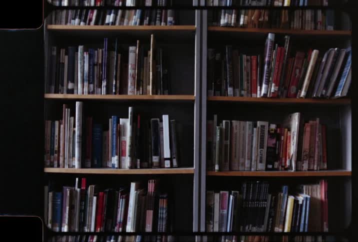 A library bookcase is filled with numerous books of various shapes and sizes