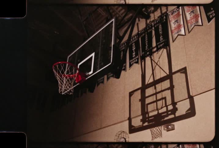 Basketball net hangs from a backboard as it casts a shadow on the wall