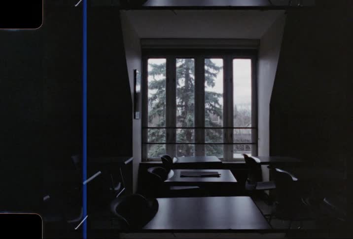 Row of school desks near window in empty darkened classroom
