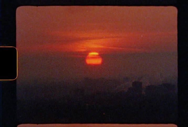 The sun sits low above the horizon as it is setting and the sky has an orange and red tint to it