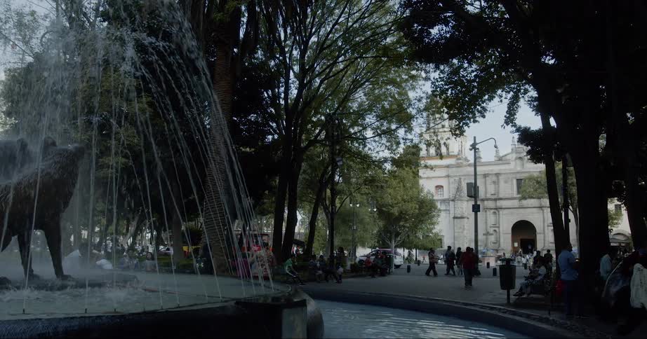 A fountain is situated at the middle of park that is filled with people