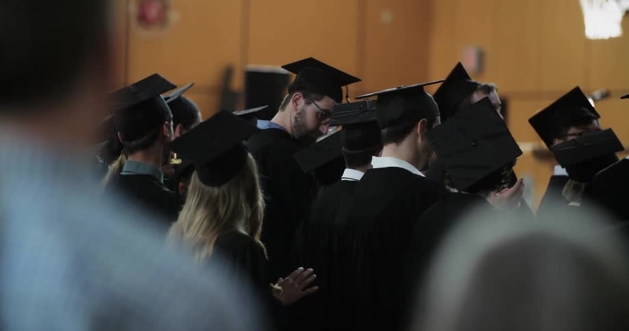 A group of people stand together wearing graduation uniforms