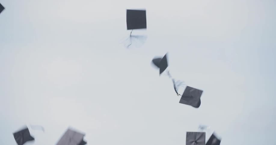 Graduates toss their caps into the air under a blue sky