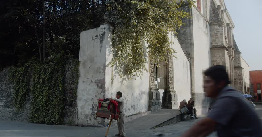 Man rides a bicycle down the street as a vendor stands on the corner