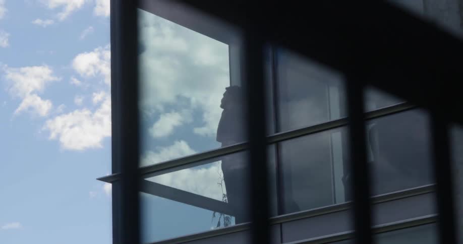 A man in a building talking on the phone looking out the window