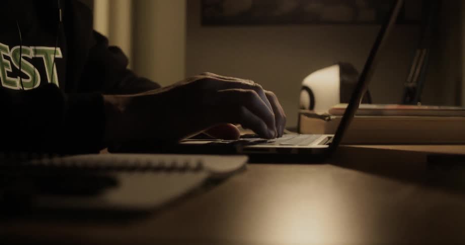 A person types quickly on a laptop sitting at a desk