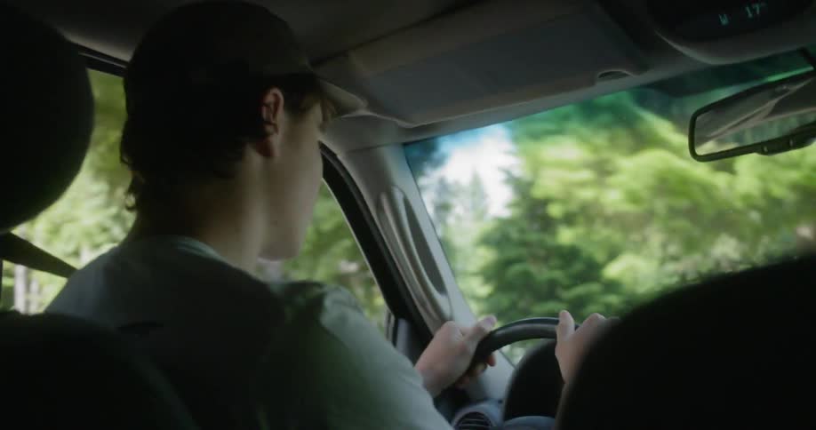 Interior shot of teenager driving a car through a neighborhood