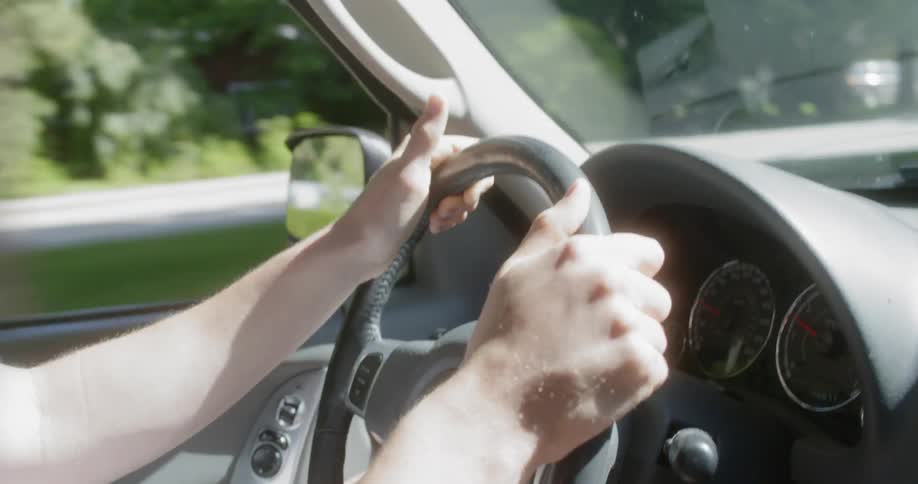 Young man smiles as he drives a vehicle on a sunny day