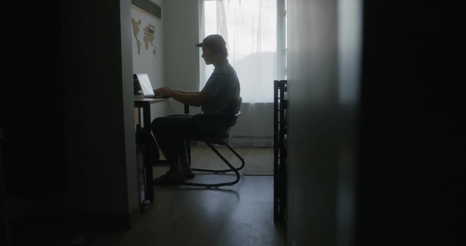 A person is writing and using his laptop in the room