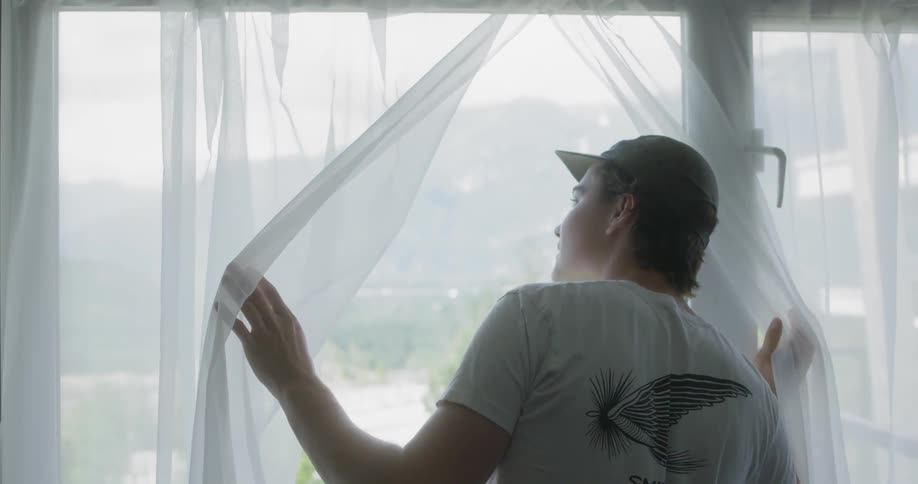 Excited teenager standing and looking out a window