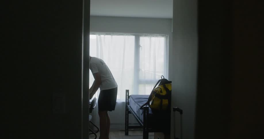 A young boy picks up papers in a his room