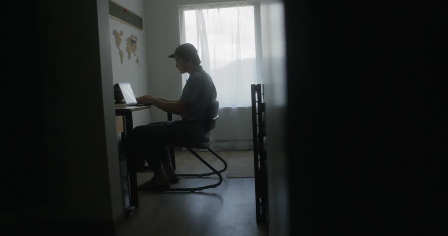 A man bops his head to music while using a laptop and headphones