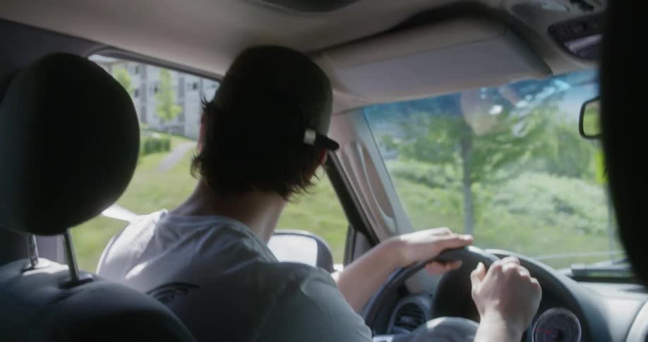 Man wearing a cap drives along the road in the city