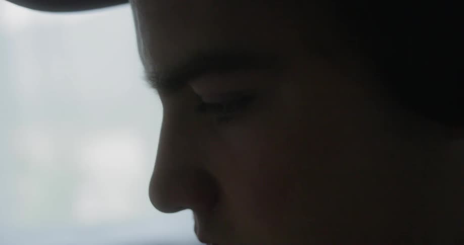 A man is wearing a hat and looking down