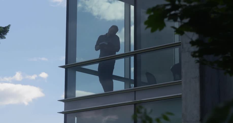 A man stands near the window while on the phone
