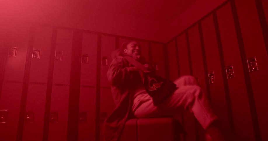 A girl sitting down dancing in a locker room
