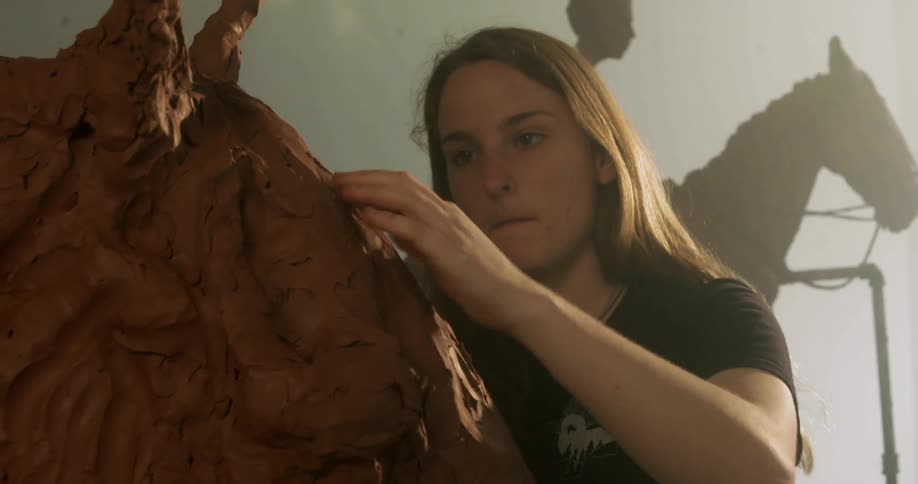 A woman sculpting a horse out of clay