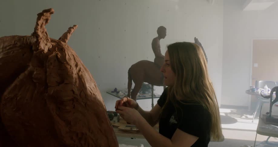 A woman sculpting a horse out of clay