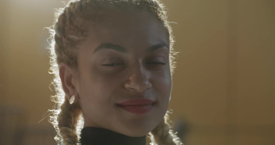 A young female turns her head to look at the camera and offers a faint smile