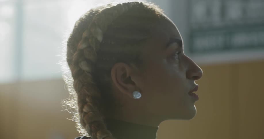 A woman standing up in a gymnasium staring off into the distance