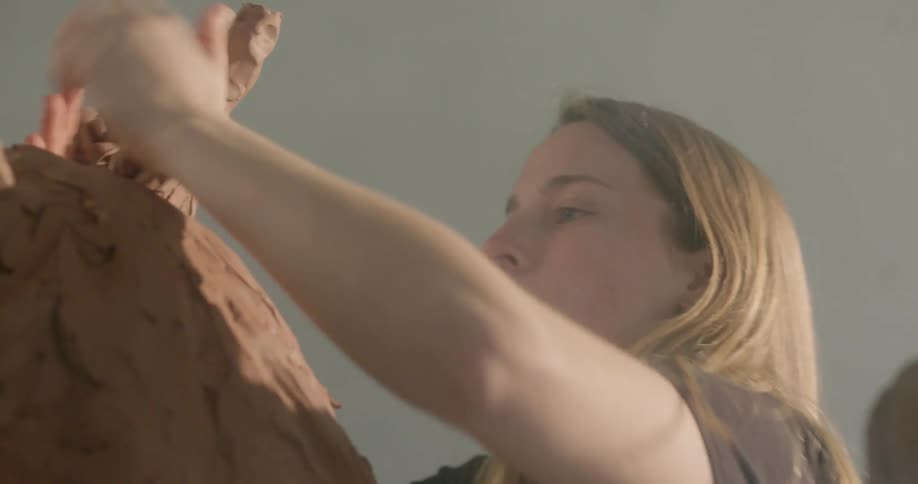 A woman sculpts with clay