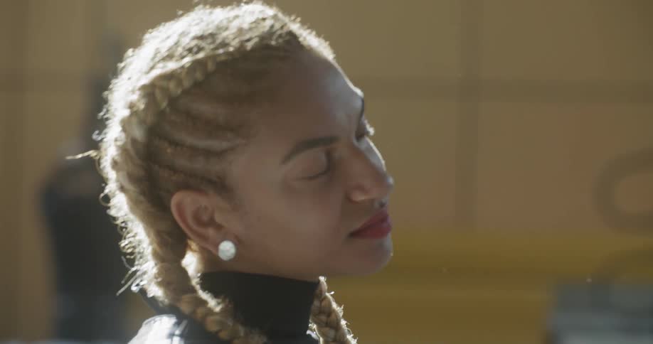 Woman with blonde braided hair tilts her head to one side and smiles