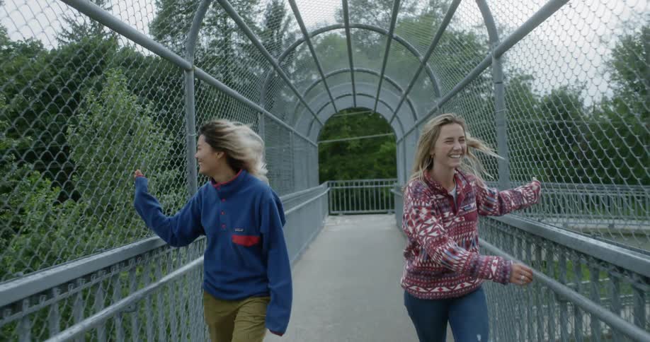 Two teenage girls walk across an elevated walkway