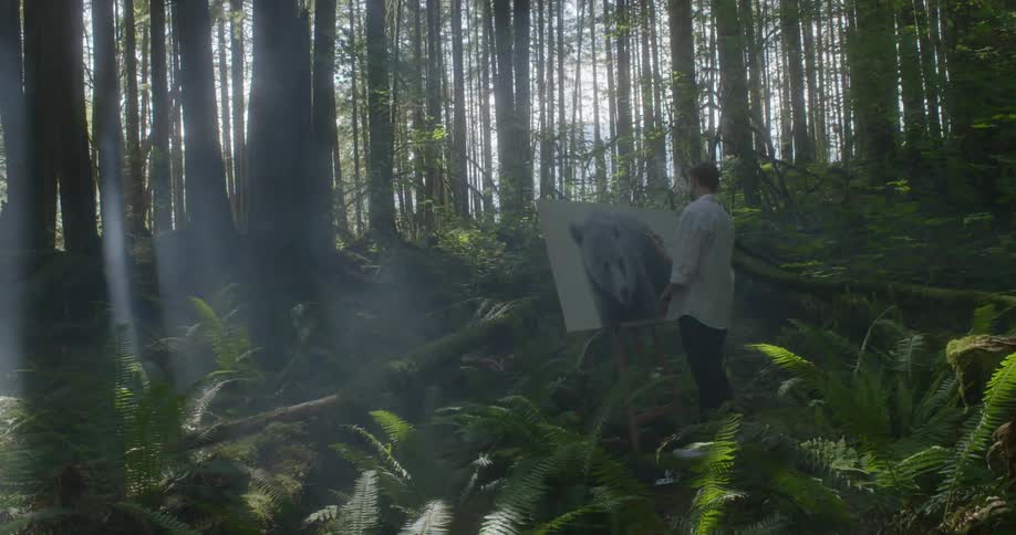 Man paints a picture of bear in the dense forest during daylight