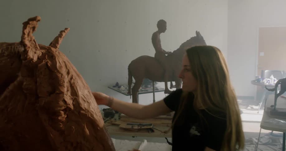 A young girl sculpts a horse
