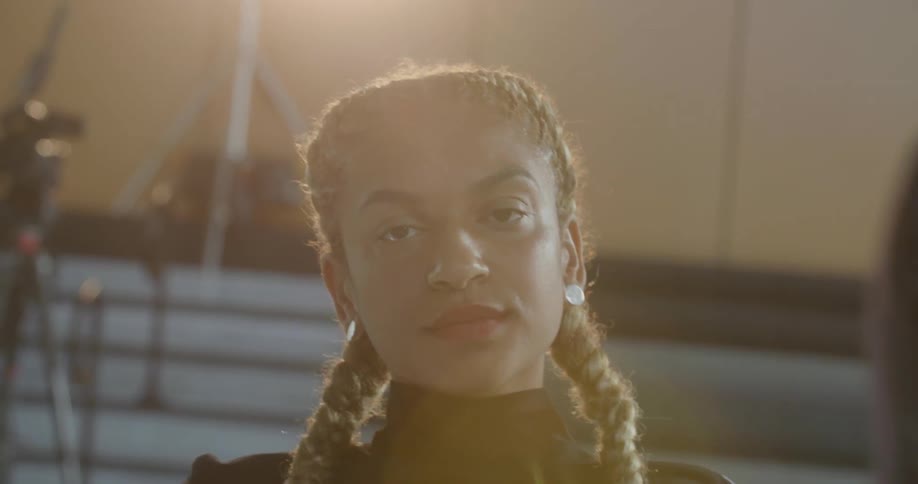 A young black woman with pigtails stares intently