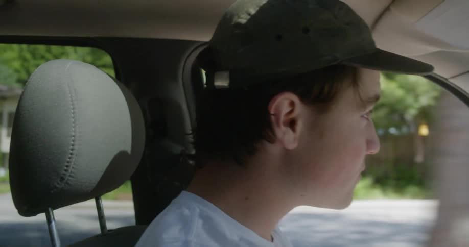 Boy wearing a cap drives through the streets of the city
