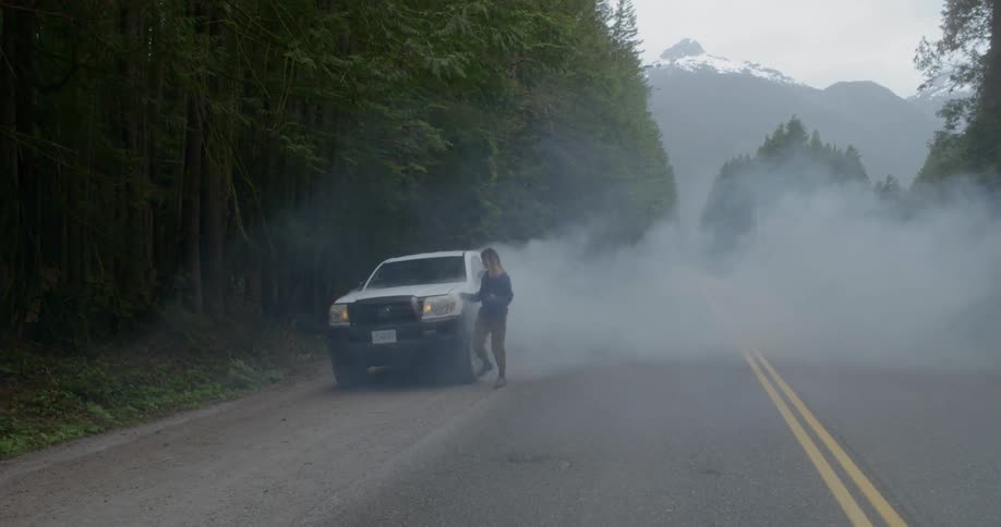 The truck on the side of the road is smoking