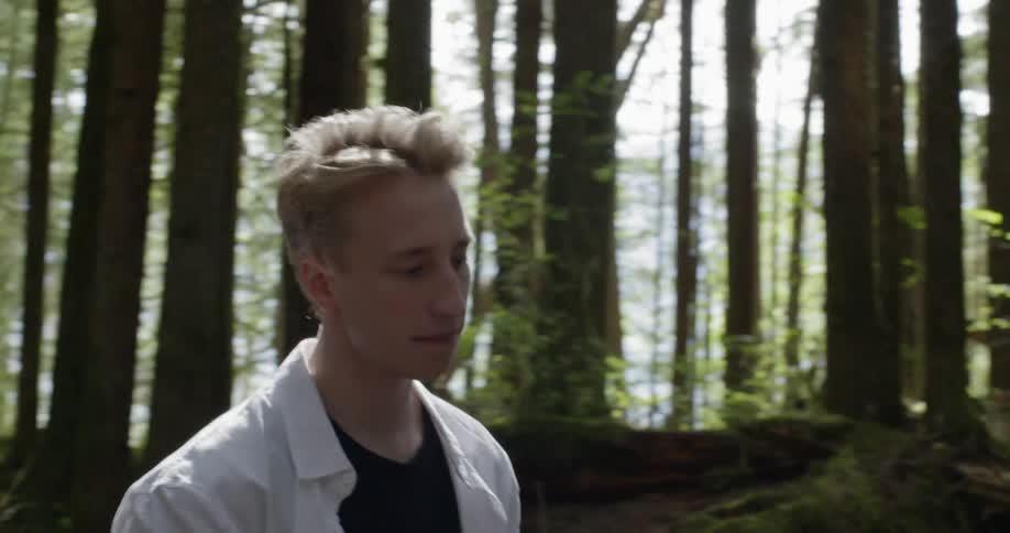 Blonde man paints a picture of bear and checks it out in the dense forest