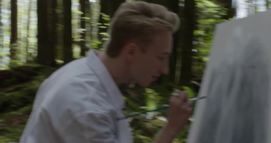 A man in the woods painting on a canvas