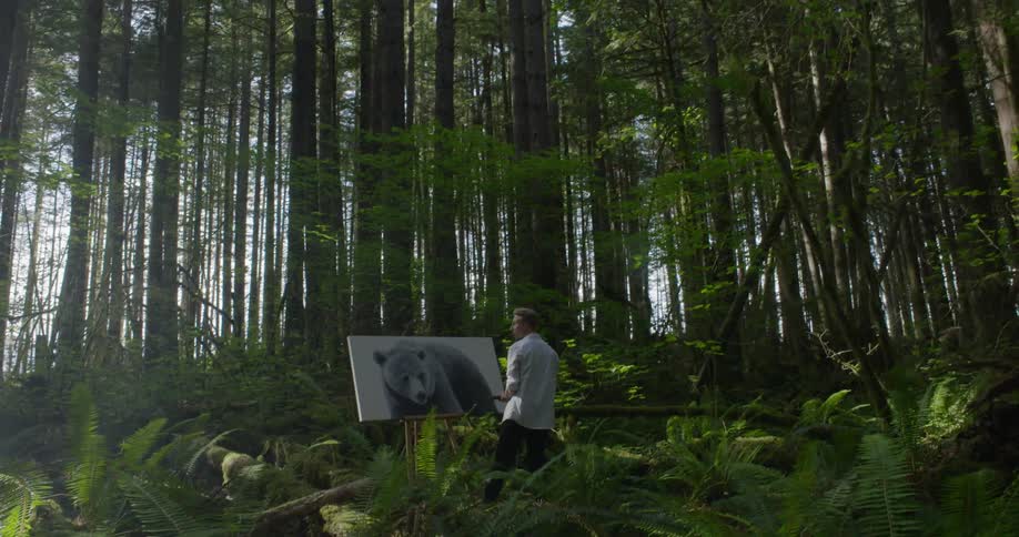 A white man paints a picture of a bear out in the woods