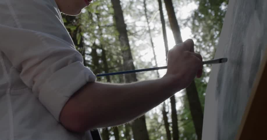 Teenager painting on canvas outdoors in a forest