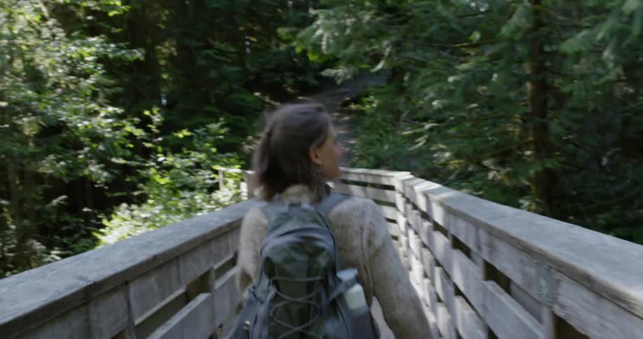 A woman walks across a pedestrian bridge while hiking